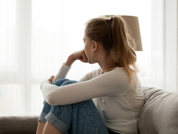 A sad young woman looking out the window.