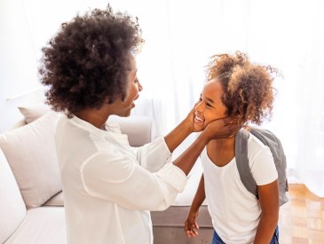 Mother preparing her daughter for first day in school.