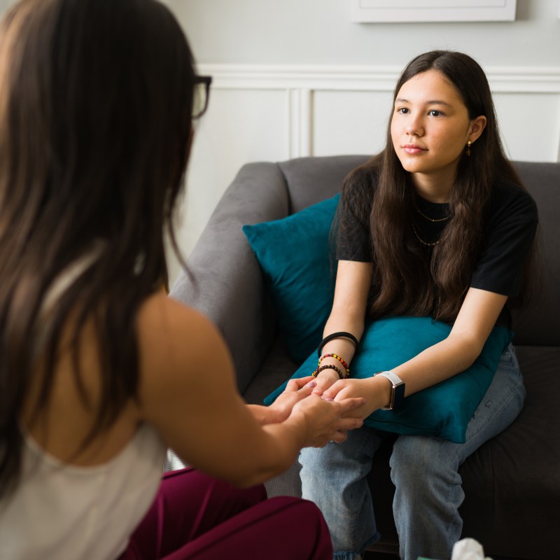 Therapist holding hands with a teen patient