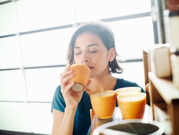 Young woman in a shop, smelling a scented candle. bath & body works candle sale, bath & body works single wick candles, bath and body works semi annual sale 2024, bath and body works single wick candle sale