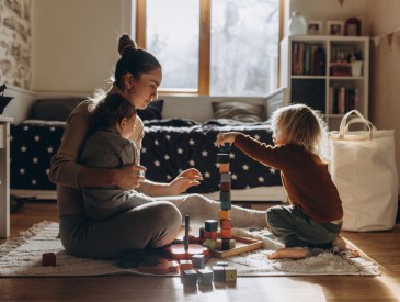 A mother and two young children playing with blocks